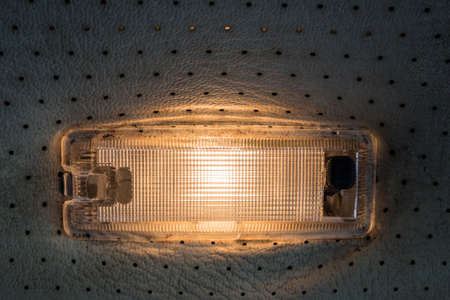 A courtesy light on the roof of a vintage car. Lamp on perforated vinyl roof.の写真素材