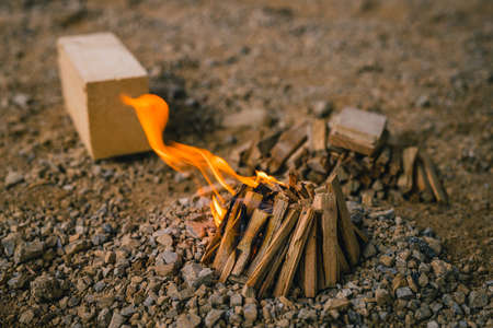 A small bonfire made by children with small logs and pricks as a part of a game. Small flame on a mini bonfire.の写真素材