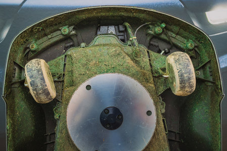 Dirty underside of robotic lawnmower, motorized lawnmower being serviced on a table after a year of use in the mud and grass. Regular maintenance of robotic lawnmowerの写真素材