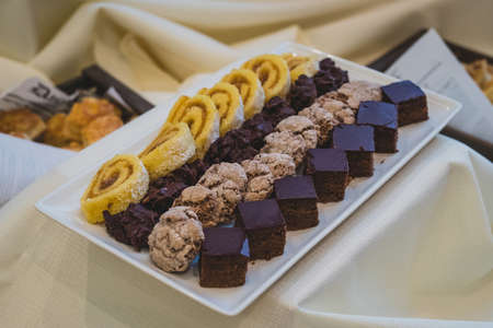 Different selection of sweets on a plate on a serving table at a banquet or feast. Catering with sweets, cookies and rolls.の写真素材