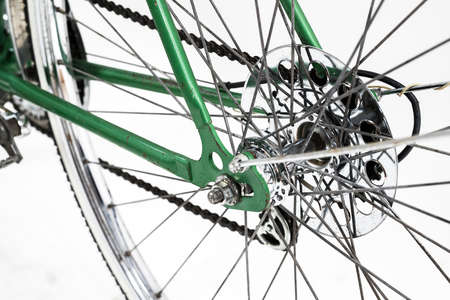 An old retro looking green vintage city bicycle for women, isolated o white background. Closeup or detail of rear hub, deraileur, casette and chain. Axle with nut is visible.の写真素材