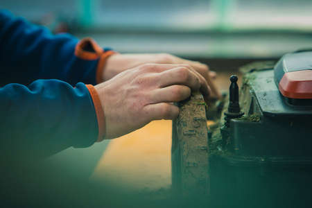 Serviceman stripping robotic lawnmower, motorized lawnmower being serviced on a table after a year of use in the mud and grass. Regular maintenance of robotic lawnmowerの写真素材