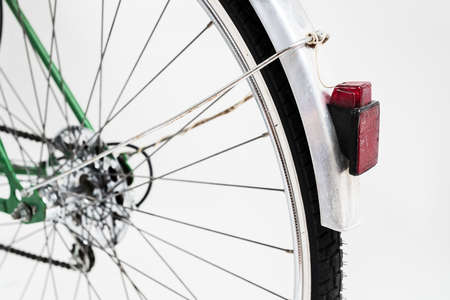 An old retro looking green vintage city bicycle for women, isolated o white background. Detail of rear red lamp and a tire.の写真素材