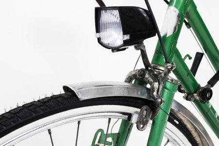 An old retro looking green vintage city bicycle for women, isolated o white background. Detail of front light and front brake with brake pads.の写真素材