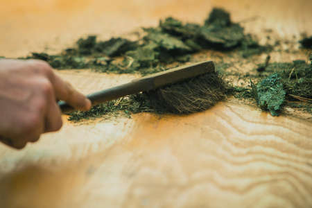 Cleaning grass debris from table with a small old broom after servicing a lawnmower. Grass residue on tableの写真素材