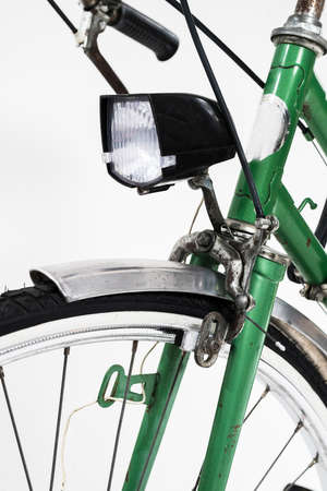 An old retro looking green vintage city bicycle for women, isolated o white background. Detail of front light and front brake with brake pads.の写真素材