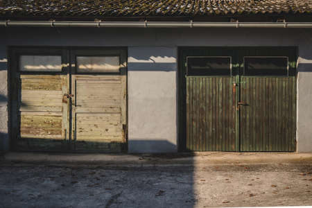 Two old and wooden garage doors in green color. Stained green color on the wooden door, locked with padlocks.の写真素材