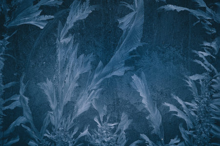 Frost pattern or flower on glass of a window. Frozen ice flower forming during the cold weather on...