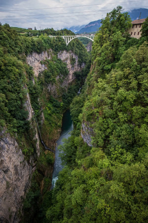 Deep gorge valley with river of Adige in the bottom behind the dam of lake Giustina in Italy, close to the city of Cles. White train bridge visible in the background.の写真素材