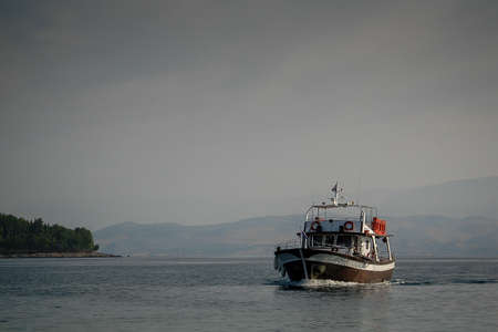 An older type of a middle sized boat or ship is naviganting on mediterranean sea close to the shore of Corfu island, Greece.の写真素材