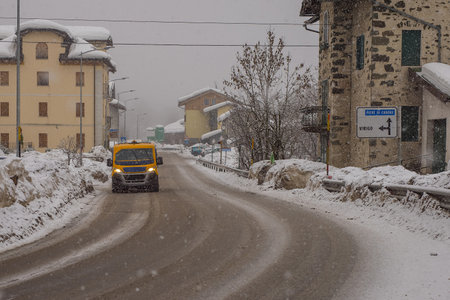 Snowy road in the village of Vodo di Cadore in Italy during heavy snow. One van is driving on a snow covered street.の写真素材