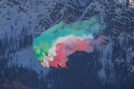 Acrobatic group of Freccia trecolori jet aeroplanes are performing maneouvres in a formation in the italian dolomites close to Cortina d'Ampezzo. Aeroplane acrobatics deep in alps.の写真素材