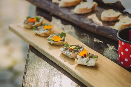 Small appetizer sandwiches on a wooden board, ready to be eaten. Fresh bread with truffles cream and...