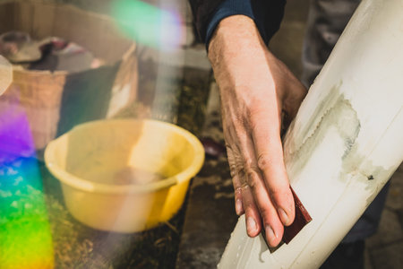Closeup of a man hand wet sanding a model aeroplane or plastic body. Man holding a 80 grit sanding...