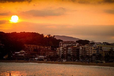 A sandy beachfront on popular tourist destination Lloret De Mar in Spain in evening with golden sun...