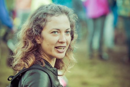 Outdoor portrait of a cute girl with brown curly hair and braces on her teeth. Insta filter, retro.