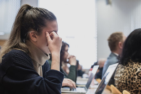 Side view of a female student listening to a lecture at an university, gymnasium or other school,...
