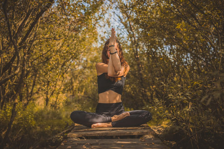 Cute brunette caucasian woman or girl practicing yoga in a beautiful fairytale autumn forest while...