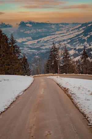 Lonely asphalt road leading down towards the valley of Adelboden, looking towards Frutigen in winter...