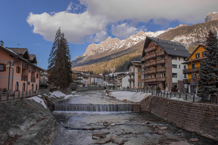 Houses and hotels in Moena, a city in italian Val di Fassa on a sunny winter day rising over the...