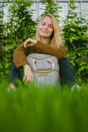 Hipster young blonde woman with septum piercing sitting on a grass in park, posing with a...