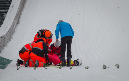 Paramedics and rescue workers helping an injured ski jumper on the bottom of the ski jump. Injured...