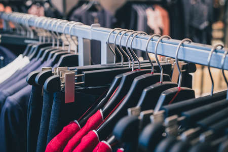 Row of many different clothes hanging on a hanger in a textile shop using classic wire and plastic hangers. Row of clothes in a shop.の写真素材