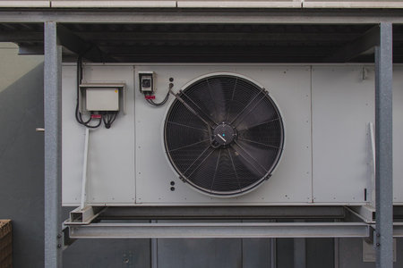 Outside part of industrial air conditioner unit mounted on a building wall, surrounded by...