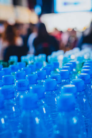 Vertical picture of a multitude of blue bottle water caps on a business conference or a seminar, waiting for thirsty participants.の写真素材