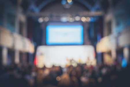 Disfocus of an audience and stage with backdrop and projector in a fancy convention hall. Background for business conference.の写真素材