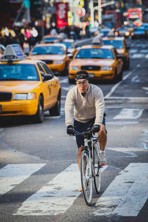 NEW YORK, USA, 9.3.2019: A keen cyclist is rushing through the dense taxy traffic in NYC on one of the avenuesのeditorial素材