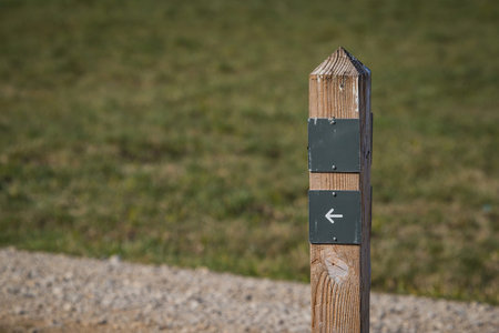 Wooden pole with gray signs bolted on. Natural background of a field or grass.