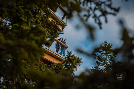 Couple standing on a tree canopy walk or treetop walkway on Rogla and looking towards camera. Beautiful walk in the outdoors, lovely young couple on a hike.の写真素材