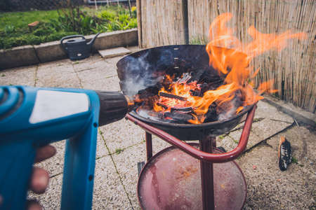 Preparation of a garden grill, heating and starting the fire with an electrical heat gun, a good help when charcoal and wood won't ignite properly.のeditorial素材