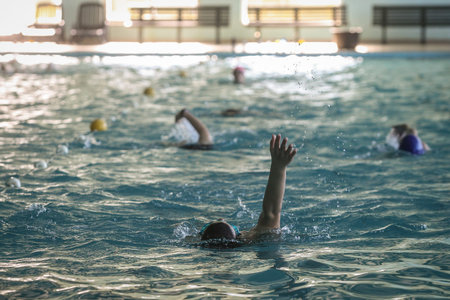 An unknown person is swimming a backstroke style in a pool. Some other swimmers in the background.