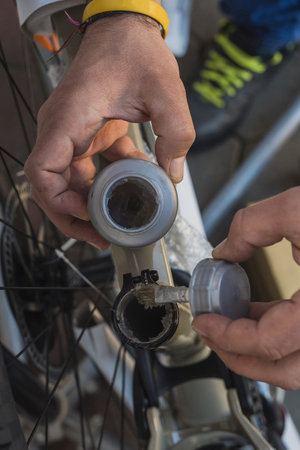 Greasing a bicycle inner seat tube, to receive a seat post. Man holding a grease container and a...