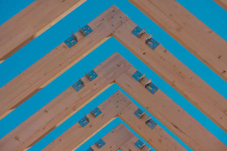 Modern wooden roof frame or frames, framework with trusses on a renovated house. Blue sky in the backgroundの写真素材