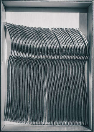 A collection of silver forks waiting in a box for hungry eaters on a gala party or eventの写真素材
