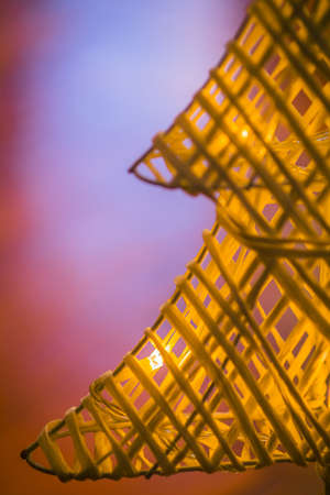 Detail of small woven christmas tree from strands or straws with warm white led lights on it. Artificial christmas tree in white color standing on the floorの写真素材