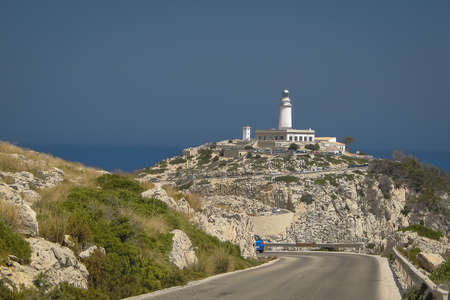 Looking towards the lighthouse on cap Formentor, Mallorca, Spain on a sunny summer day. A lot of rocks in the foreground.and a road leading to the lighthouse.の写真素材