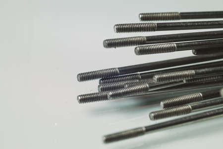 Bicycle spokes. Macro photo of a threaded part of a bicycle spokes lying on the ground on a white reflective background. Pile of spokes ready to be installedの写真素材