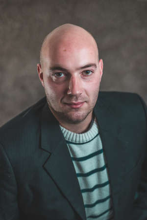 Portrait of modern business hipster crypto man in a striped sweater and a black dress or jacket on a grey background. Corporate portrait of young business manの写真素材