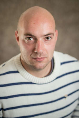 Portrait of modern business hipster crypto man in a striped sweater on a grey background. Informal portrait of young business manの写真素材