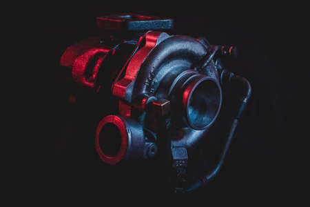 An old reconditioned car turbine, turbocharger, isolated on black with red and blue lighting.の写真素材
