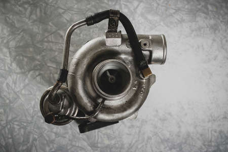 An old reconditioned car turbine, turbocharger, on a working table with vintage texture.の写真素材
