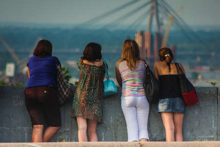 A group of women is leaning on a wall and enjoying the panorama of the city of Kiev in Ukraine.の写真素材