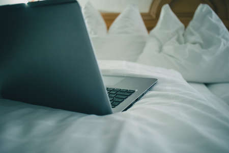 Detail view of a laptop keyboard sitting on a bed in hotel room. Vintage hotel room with laptop on the sheet. Concept of online hotel booking.の写真素材