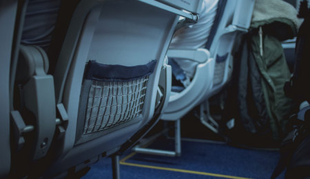 Mesh fabric pocket on the back side of aeroplane seat backrest. Pocket for storing telephone,...