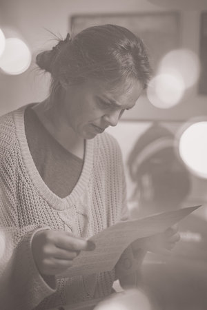 Curious woman reading paper documents obtained from a metal case. Woman reading old papers or bills,...