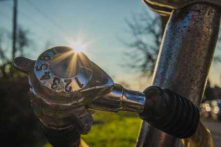 Detail of cheap worn number combination lock on an old bicycle, with sun streak or flare just behind the lock. Park setting or outside in suburb of a cityの写真素材